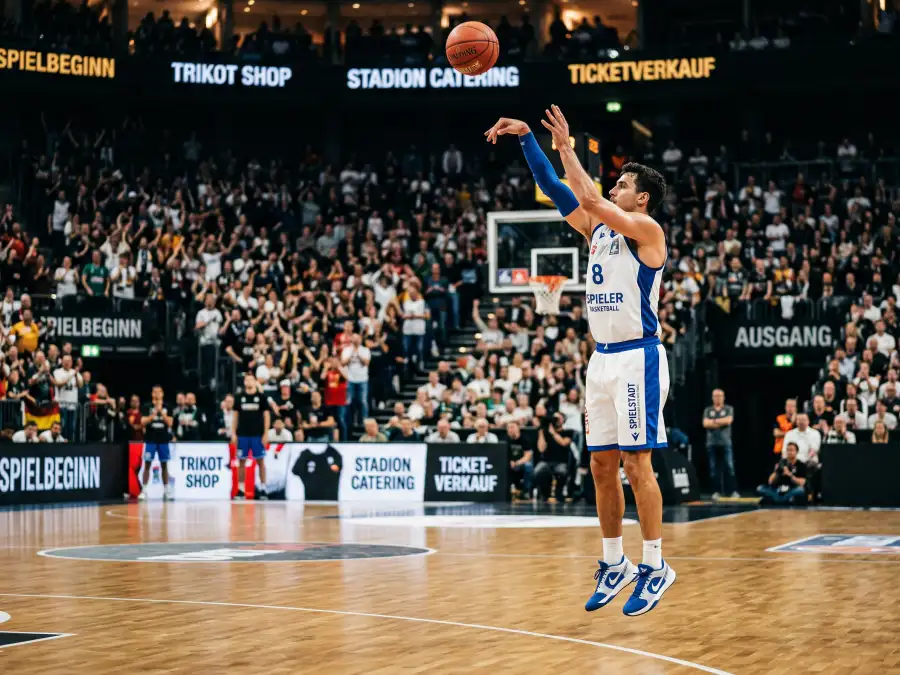 Basketballspieler beim Dreipunktwurf mit Ballflug Richtung Korb als Sinnbild der Drei-Punkte-Revolution